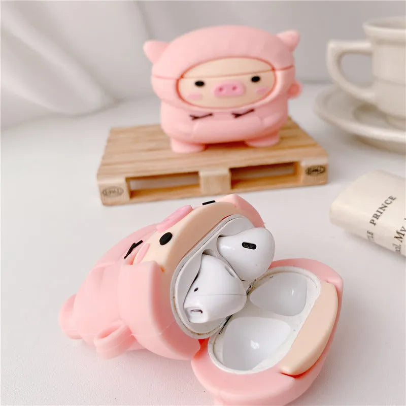Soft pink silicone AirPods case cover with a cartoon pig graphic and a matching metal carry hook.