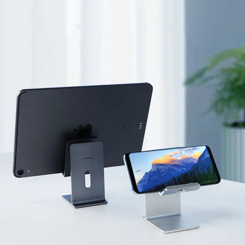 Alloy metal desktop stand holding a mobile phone, shown in dark space grey and streaming silver colours.