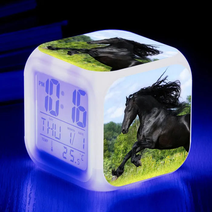 Square cartoon-style LED digital alarm clock showing time and temperature on a desk.