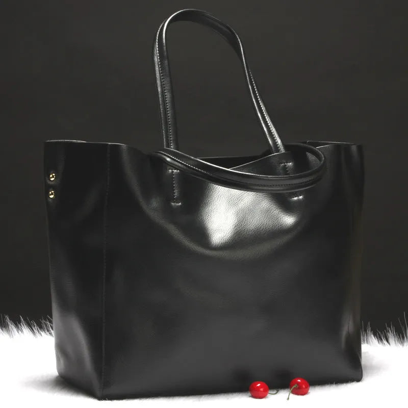 Women's cowhide leather shoulder bag in black with adjustable strap showing interior liner compartment