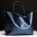 Women's cowhide leather shoulder bag in black with adjustable strap showing interior liner compartment