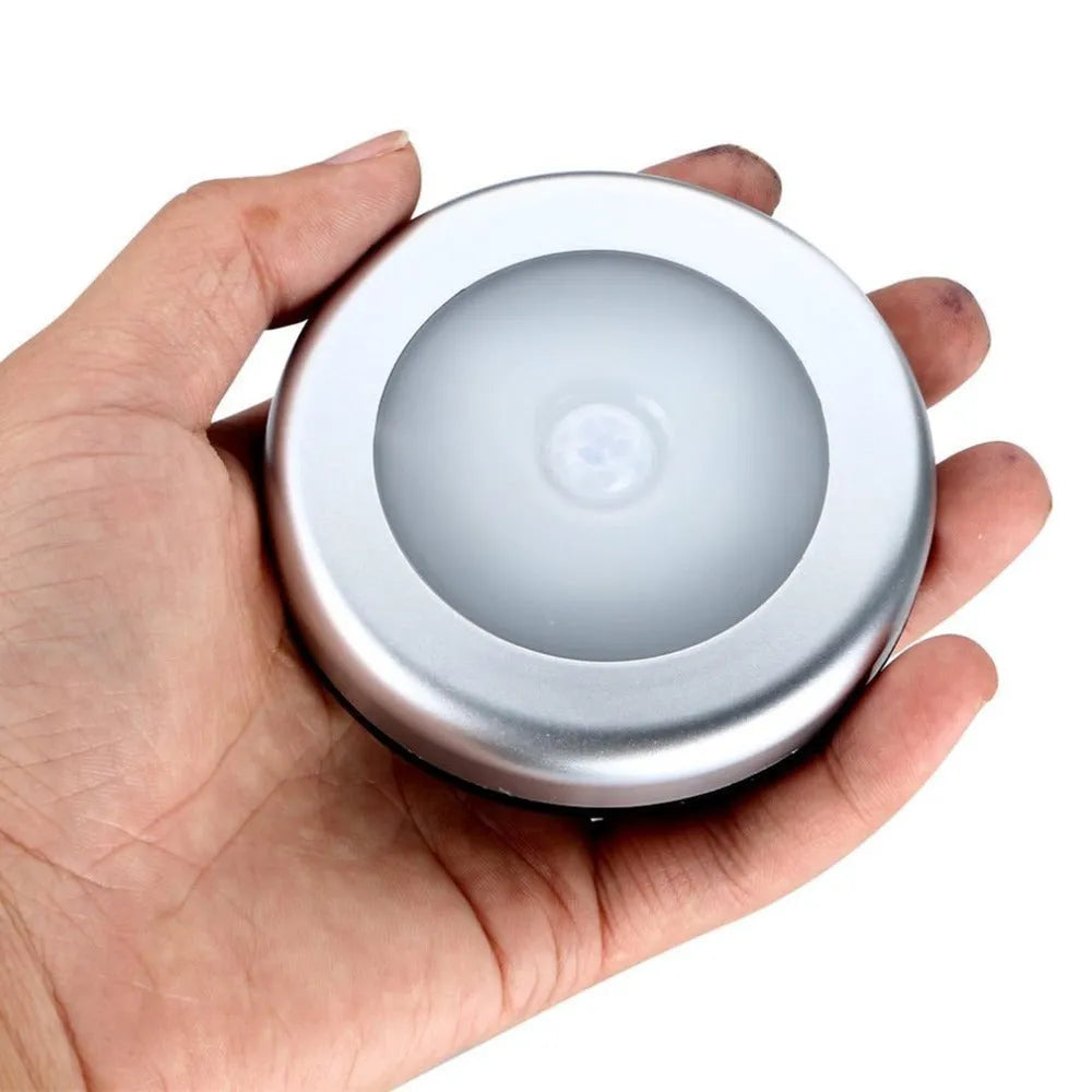 Silver wireless motion sensor night light on a table, showing its compact 80mm size.