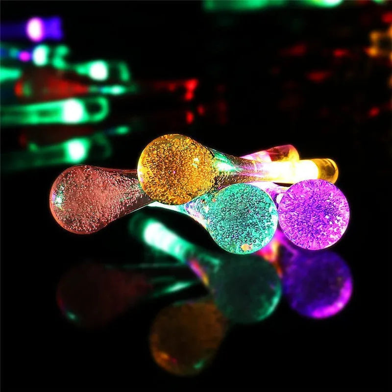 Solar-powered outdoor water drop LED string lights with warm white illumination on 6.5 metre waterproof cord
