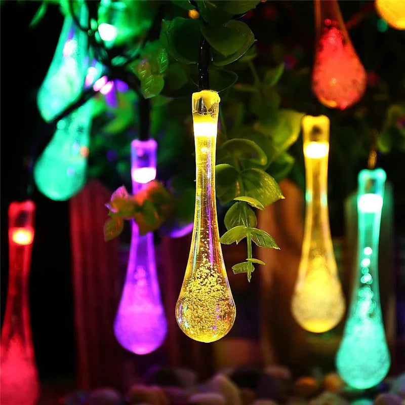 Solar-powered outdoor water drop LED string lights with warm white illumination on 6.5 metre waterproof cord