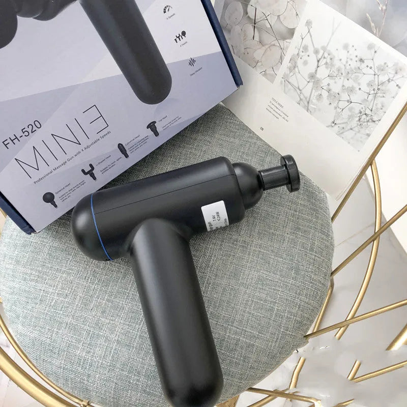 Black handheld fascia gun massager with USB port on a grey background.