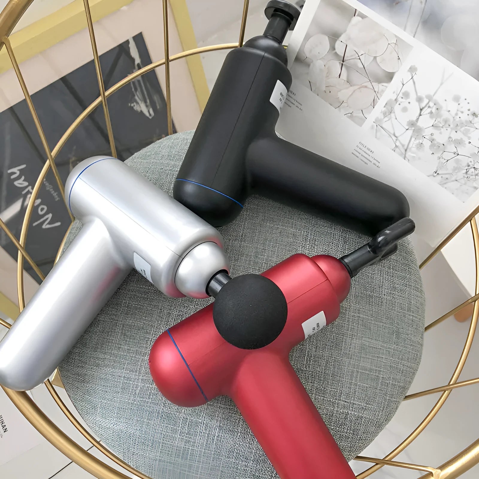 Black handheld fascia gun massager with USB port on a grey background.