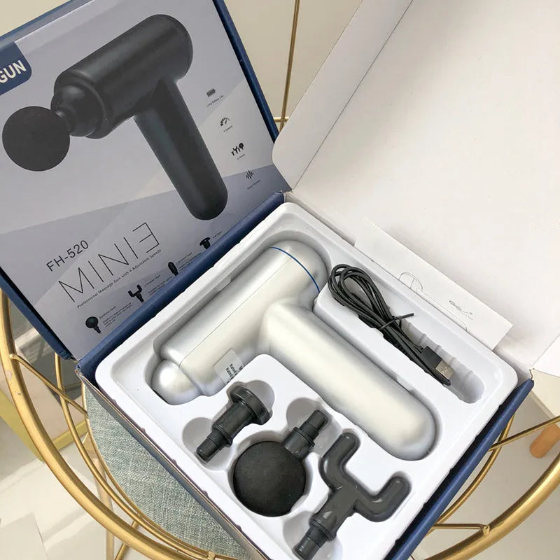 Black handheld fascia gun massager with USB port on a grey background.
