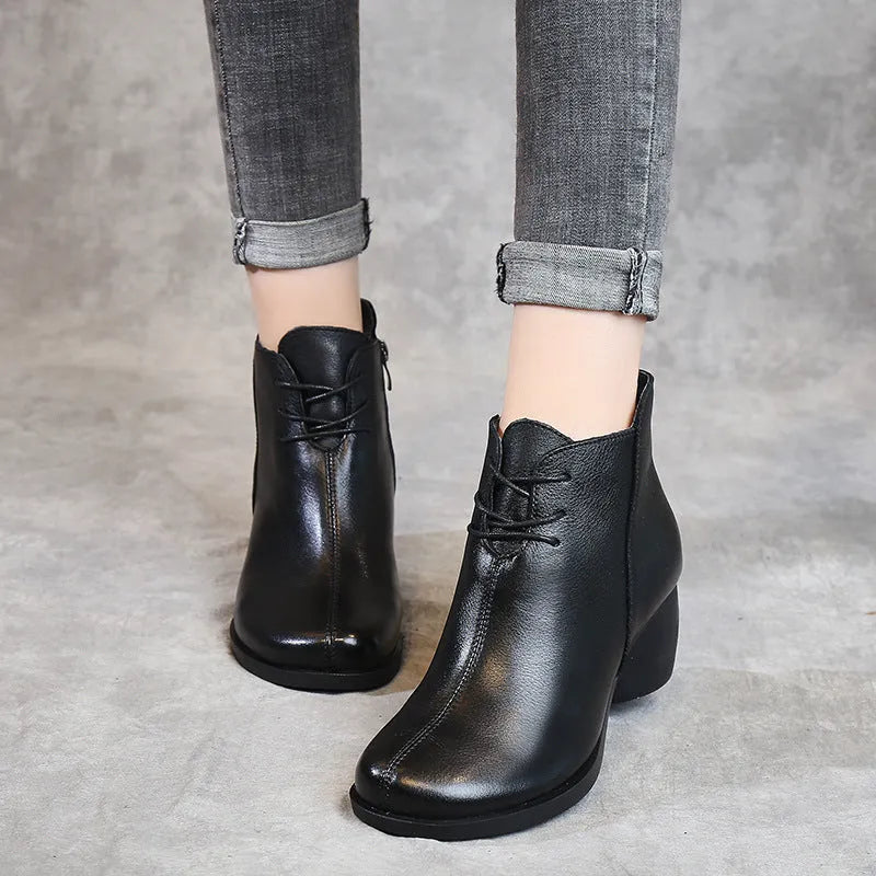 Women's black leather Martin boots with a thick middle heel and round toe on a white background.