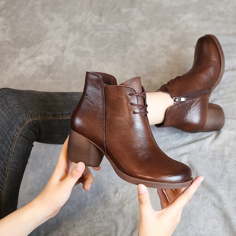 Women's black leather Martin boots with a thick middle heel and round toe on a white background.