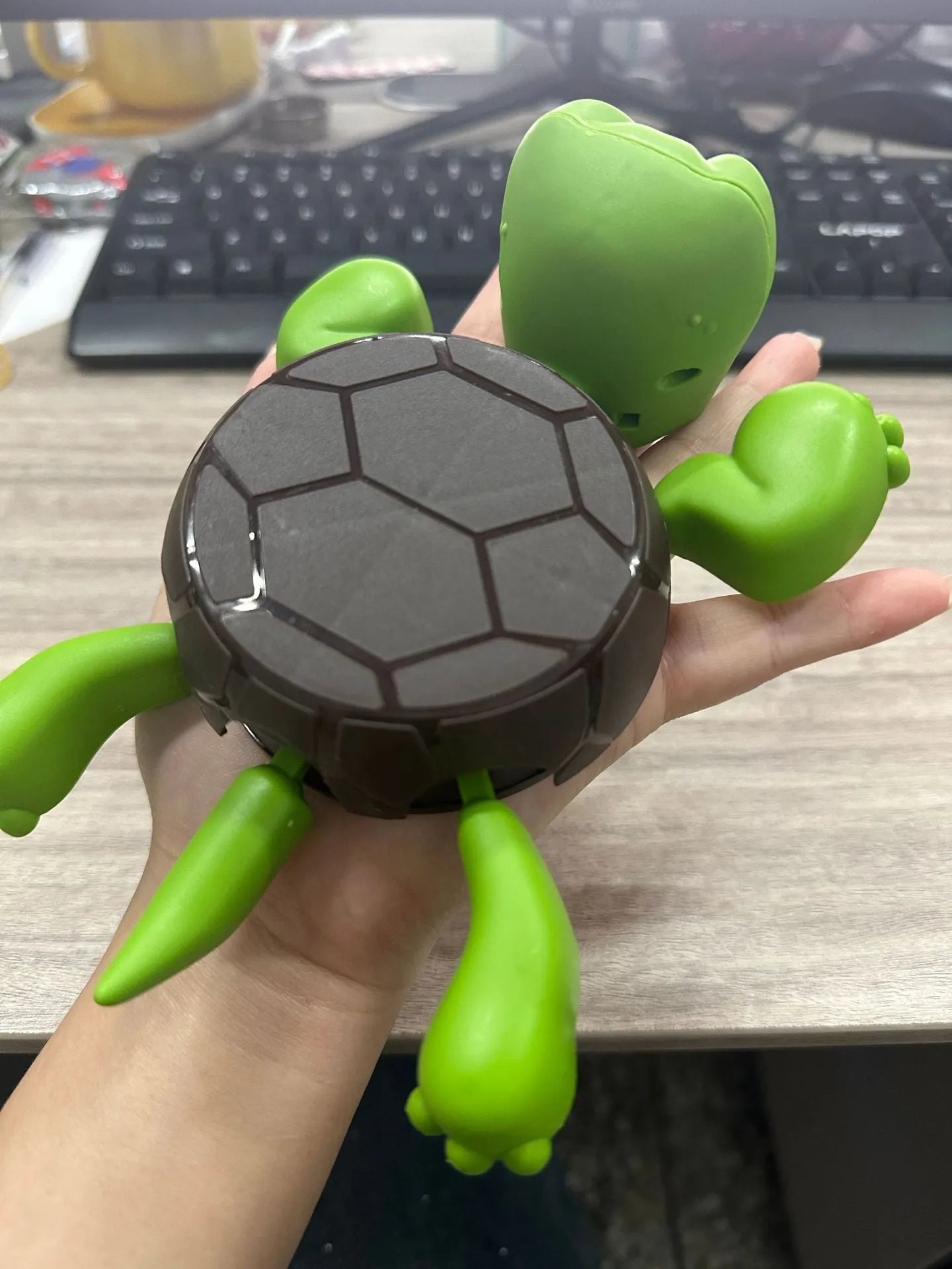 Turtle-shaped ceramic style coaster in green and yellow colours on a wooden table