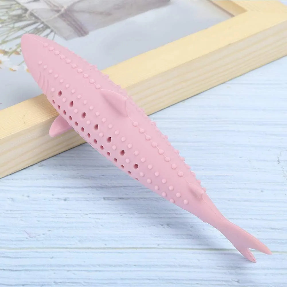 Green silicone fish-shaped cat chew toy with breathable side holes on wooden floor