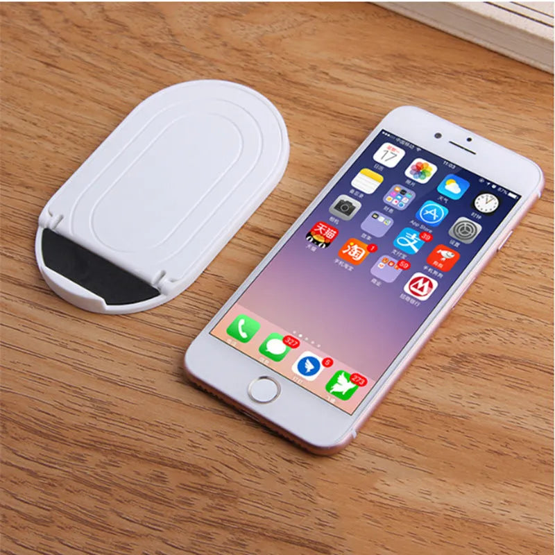 Plastic mobile phone stand with adjustable bracket in six colour options on a wooden desk