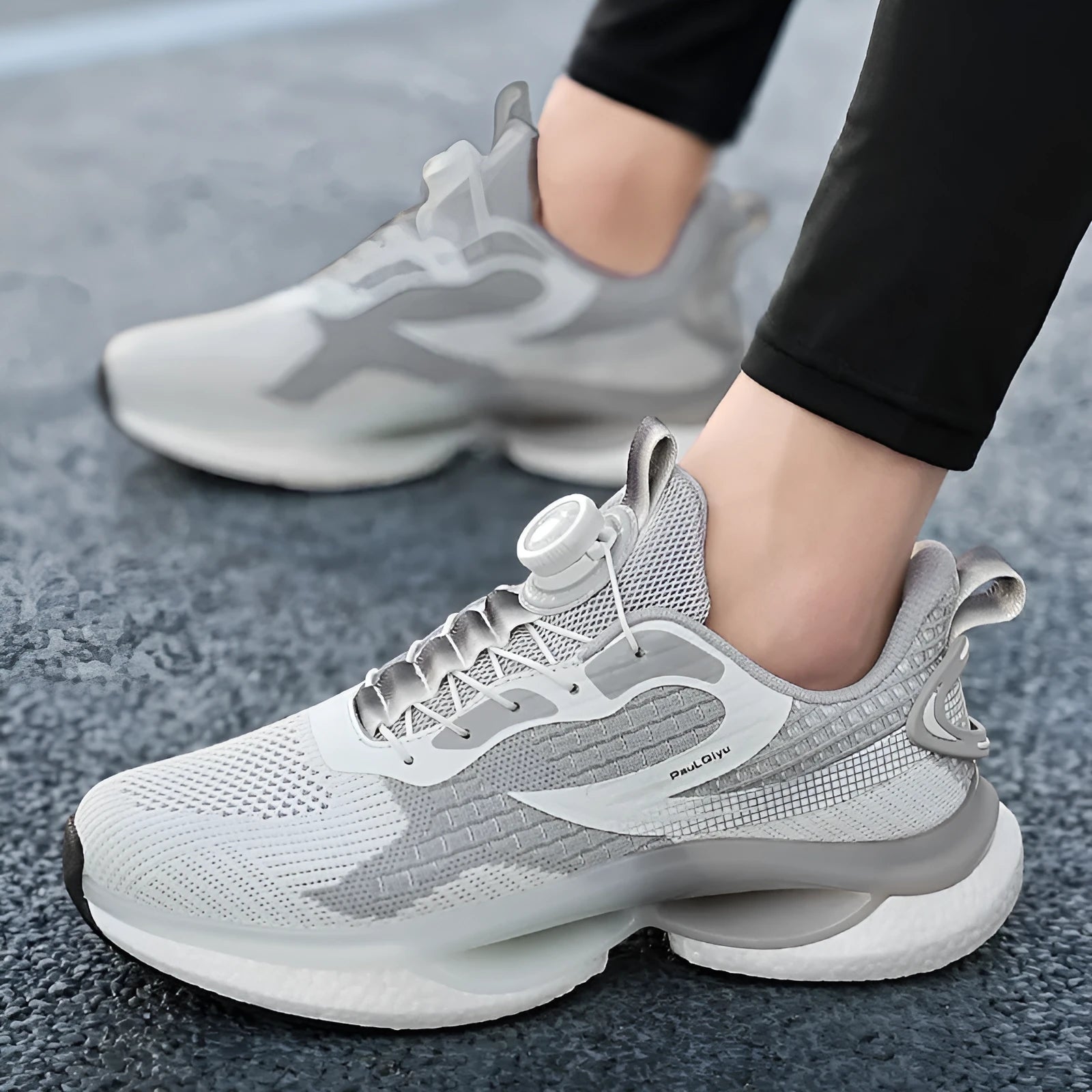 White low-top running shoes with a rotating buckle closure and Fly-knit mesh upper.