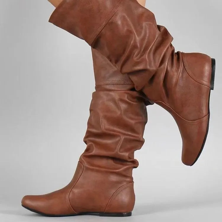 Women's flat slip-on long boots with round toe in black, shown on a foot.