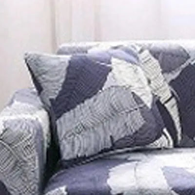 Geometric abstract printed stretch sofa slipcover covering a three-seater sofa with matching cushion covers.