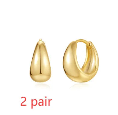 Golden brass earclip earrings with geometric round drop design on white background