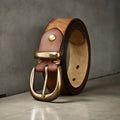 Men's brown casual leather belt with copper pin buckle on a jeans background.