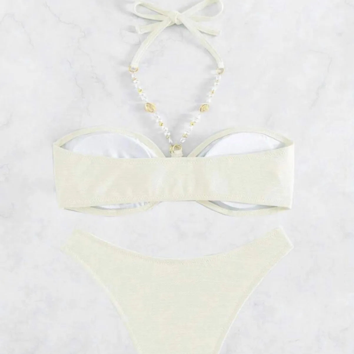 Women's creamy-white halter top and briefs bikini set for swimming on a beach