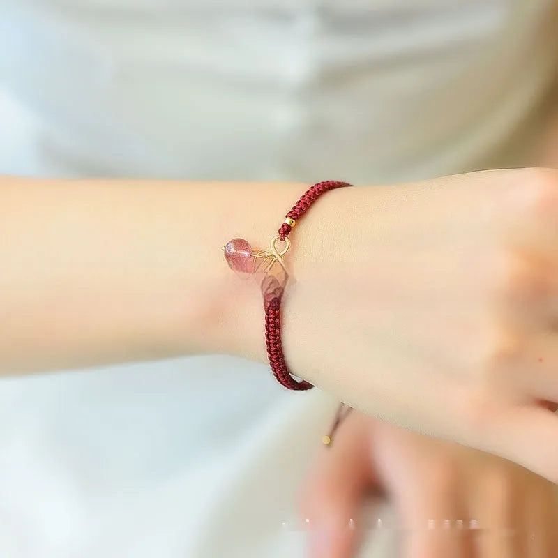 Women's natural strawberry quartz bracelet with a fruit-shaped crystal charm on wrist.