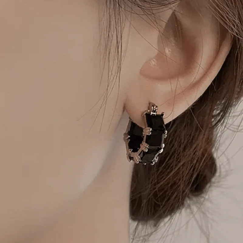 Gold geometric U-shaped women's earrings with a round black zircon stone.