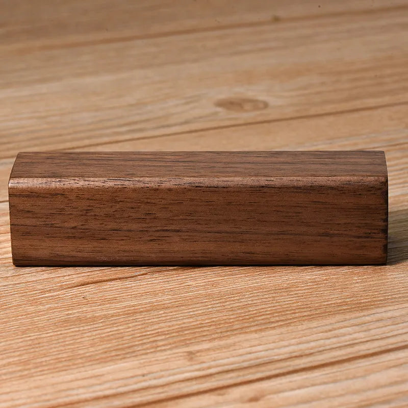 Brown black walnut wood portable power bank showing size next to a charging cable