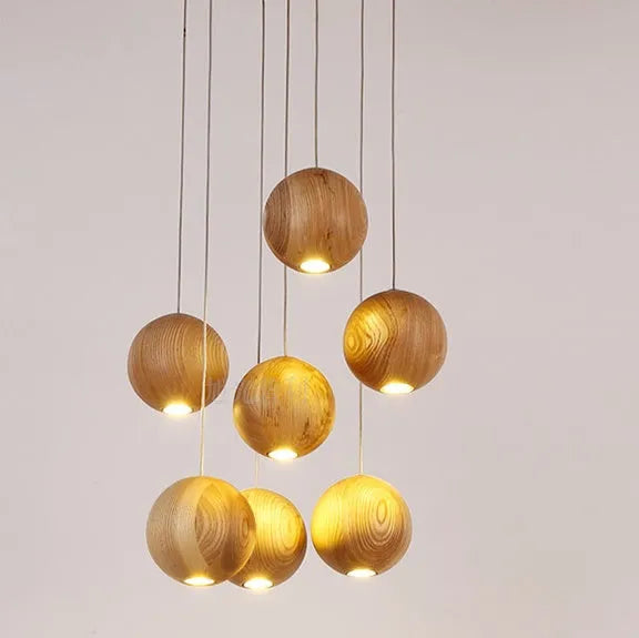 Nordic solid wood ball chandelier hanging lamp with adjustable cord over a dining table.