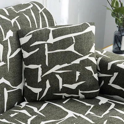Geometric abstract printed stretch sofa slipcover covering a three-seater sofa with matching cushion covers.