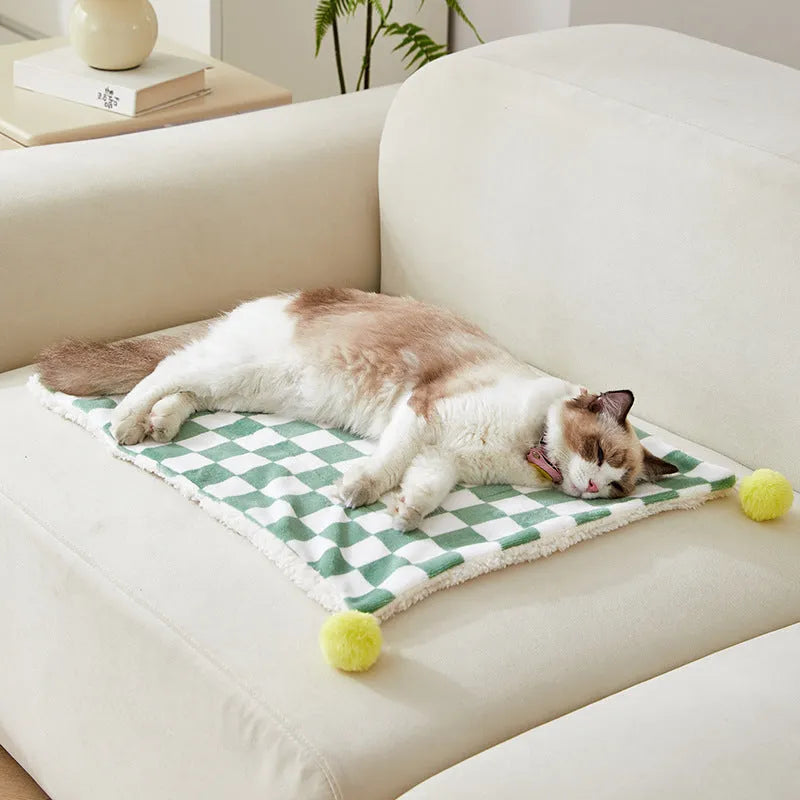 Plush pet blanket with plaid pattern and decorative fur ball in green colour