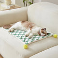 Plush pet blanket with plaid pattern and decorative fur ball in green colour