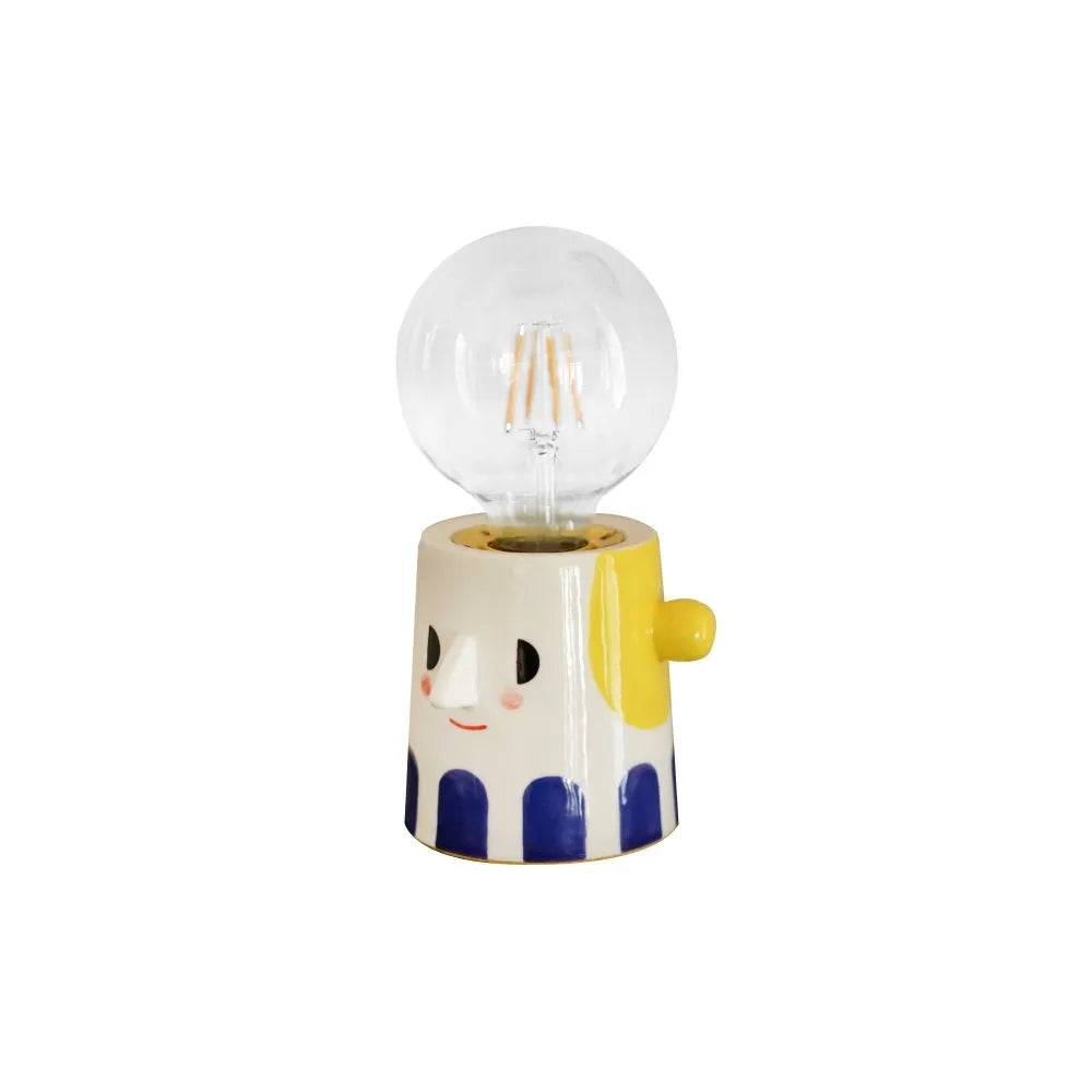 Handmade ceramic bedside lamp with a ball headlight design on a table.