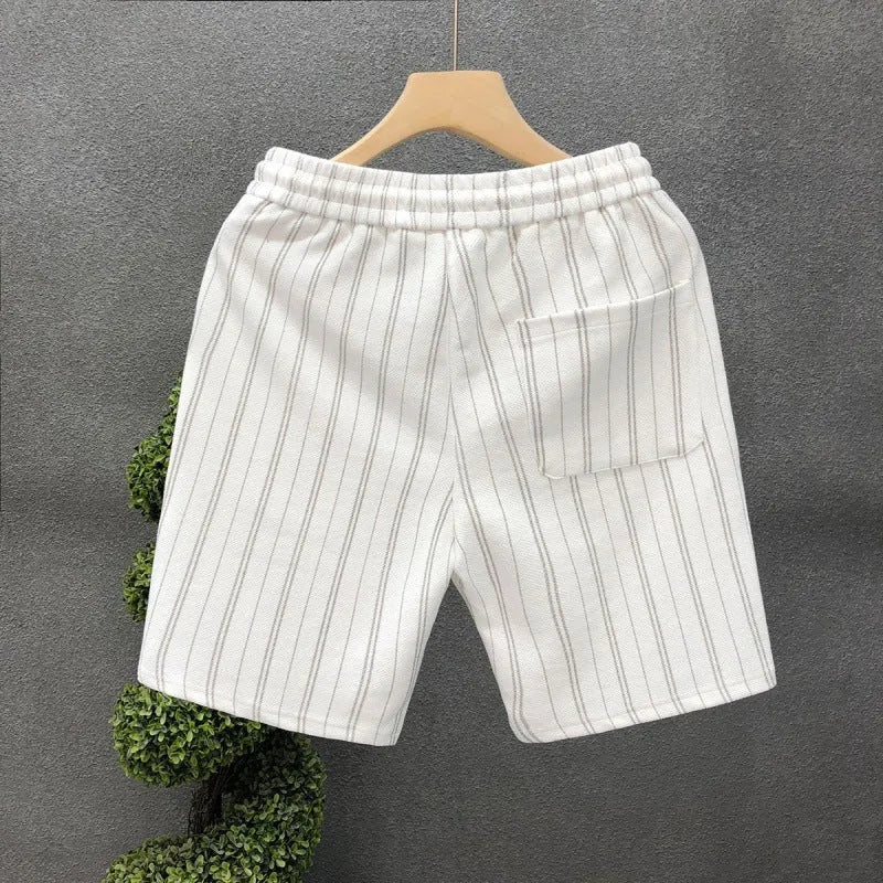 Man's black and white striped casual shorts with elastic waistband on a plain background.