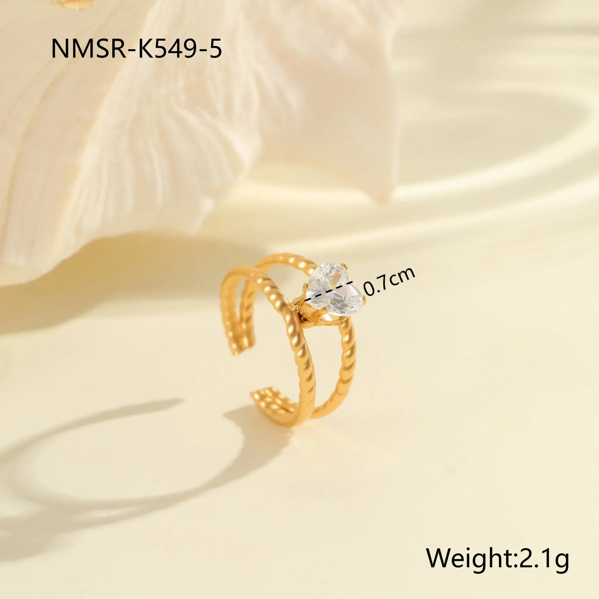 Gold inlaid zircon geometric heart and drop shape stainless steel ring on white background.