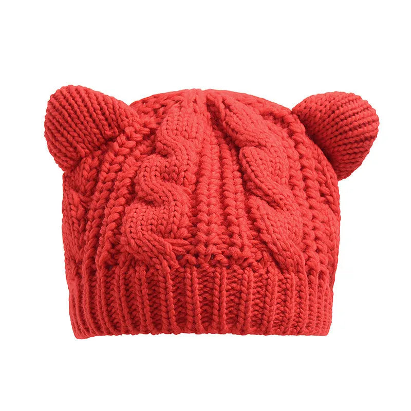 Handmade red knitted beanie with 3D cat ears on a white background.
