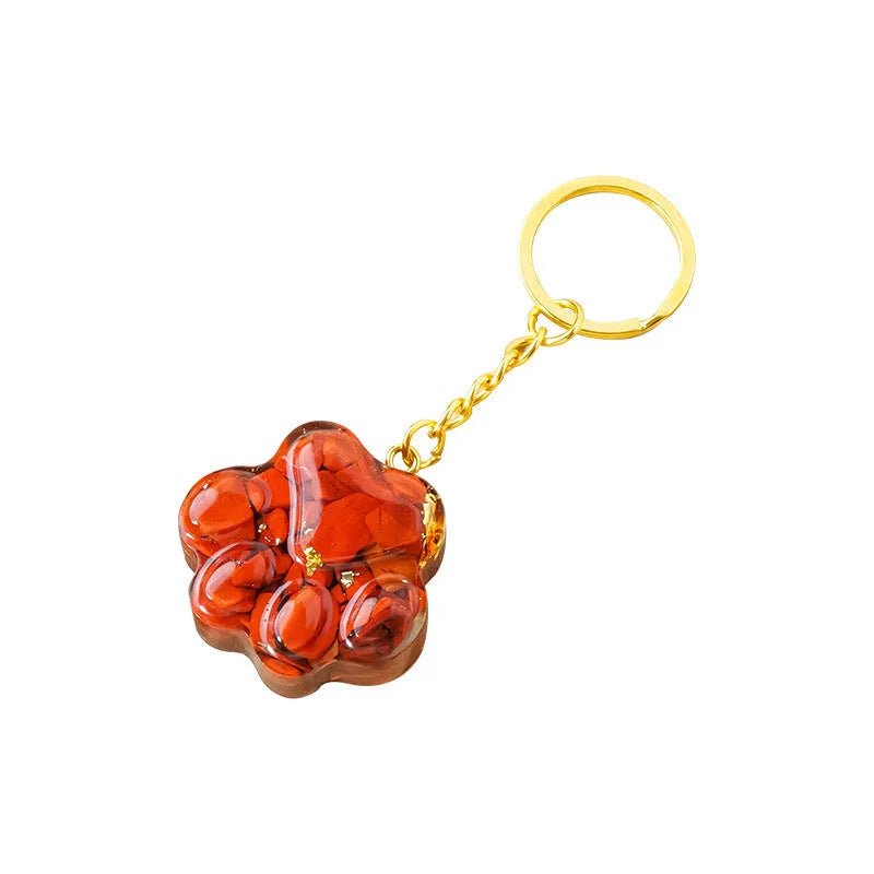 Natural crystal cat's paw shaped keychain charm on a keyring, showing colour variations of different gemstones.
