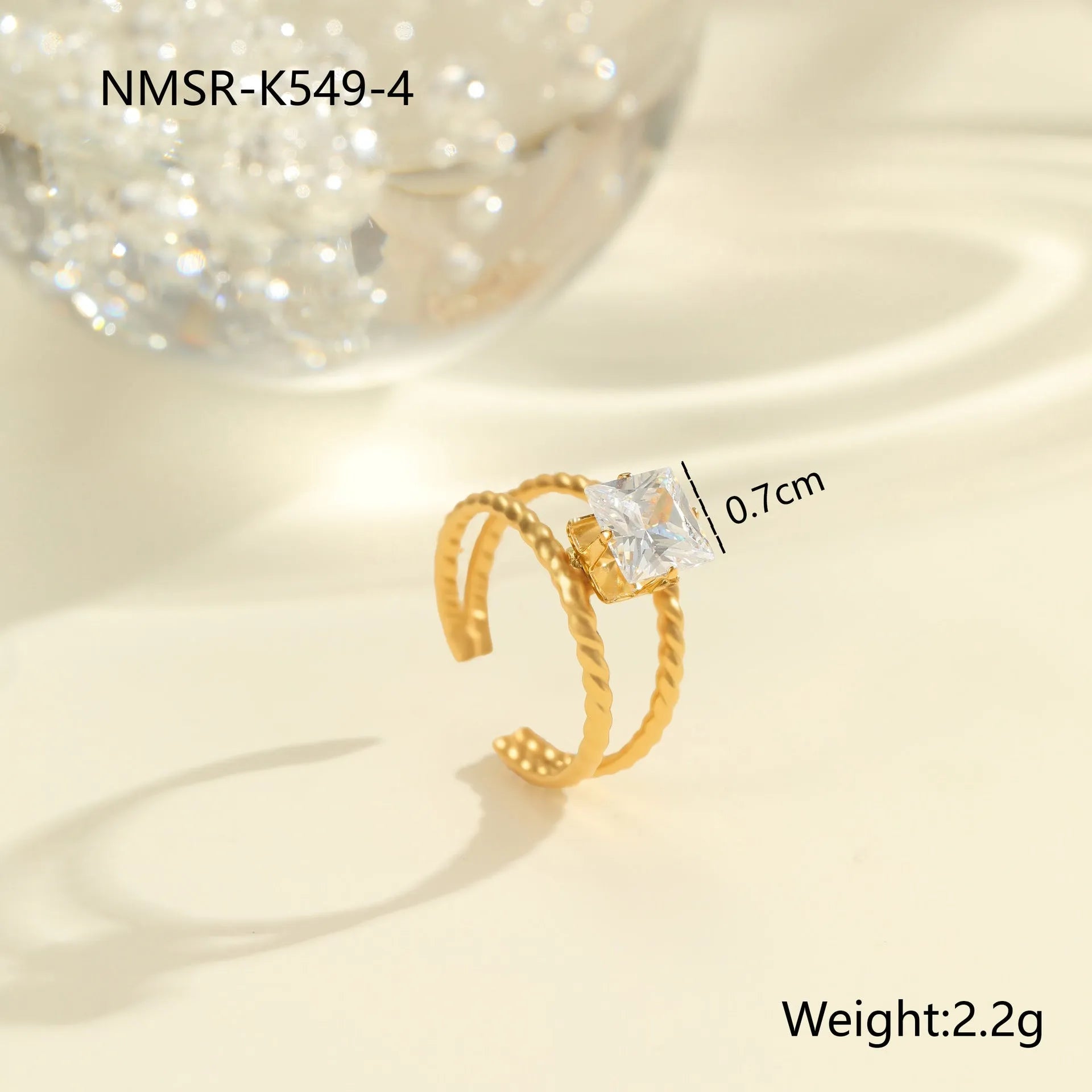 Gold inlaid zircon geometric heart and drop shape stainless steel ring on white background.