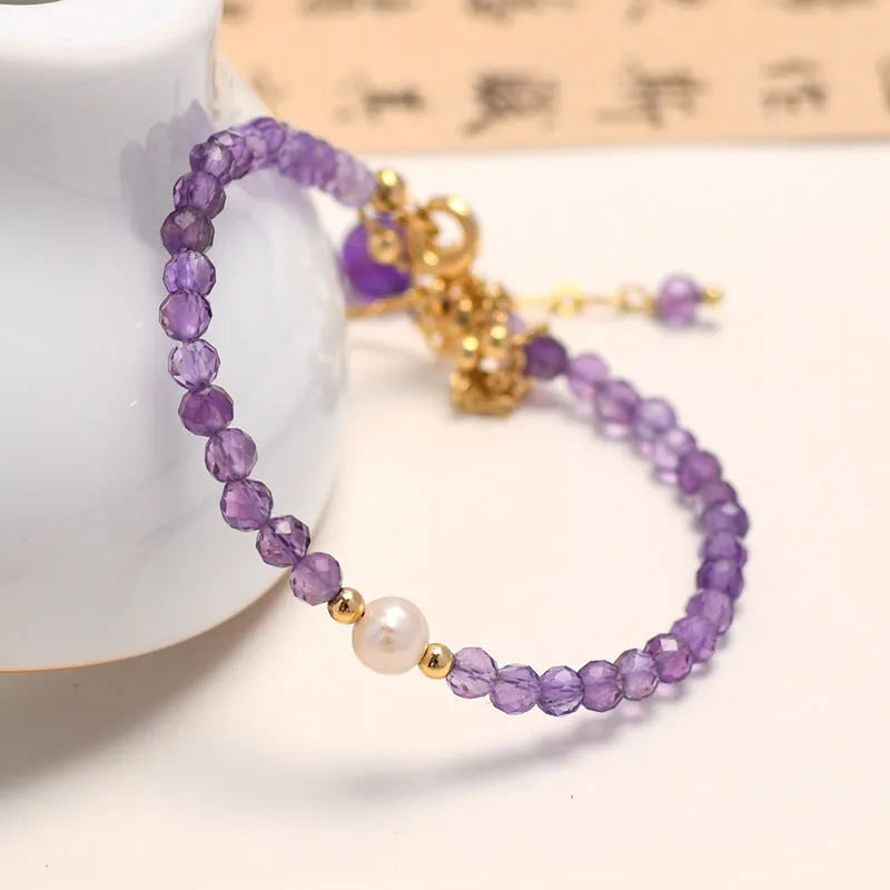 Close-up of a Chinese style women's bracelet with a diamond-shaped amethyst crystal on an electroplated chain.
