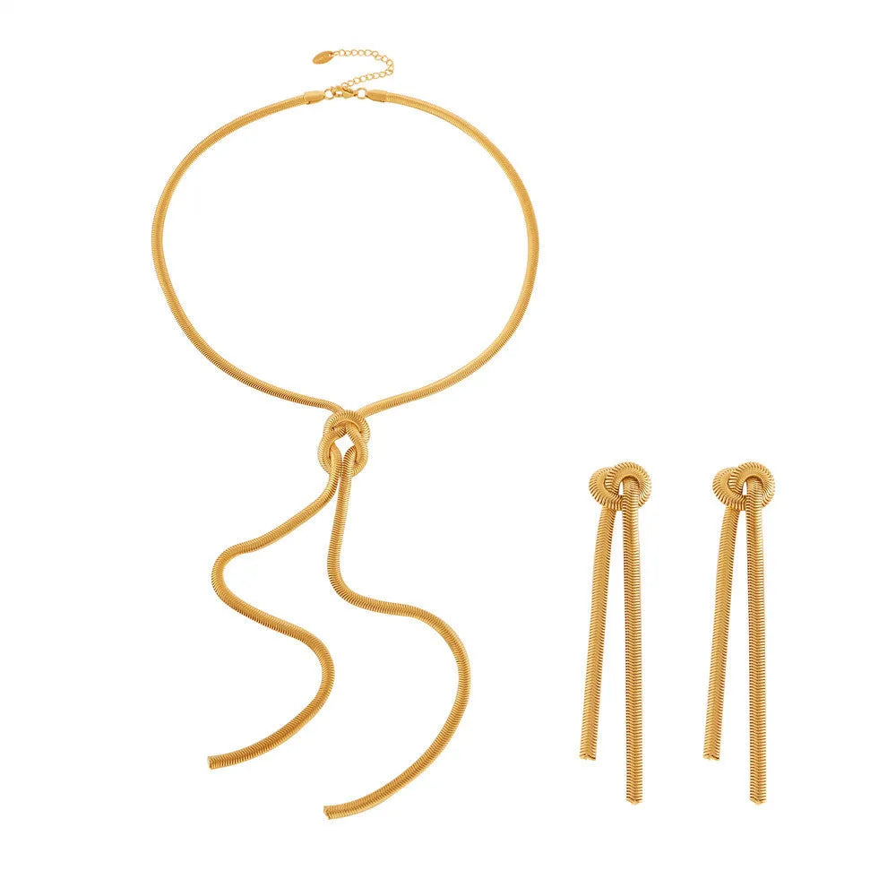 Gold titanium steel long necklace with knotted tassel pendant and matching earrings on a white background.