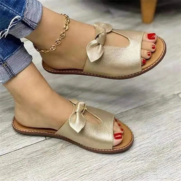 Ladies casual sandals with a bow detail and fish mouth slipper style in black, pink, or gold.
