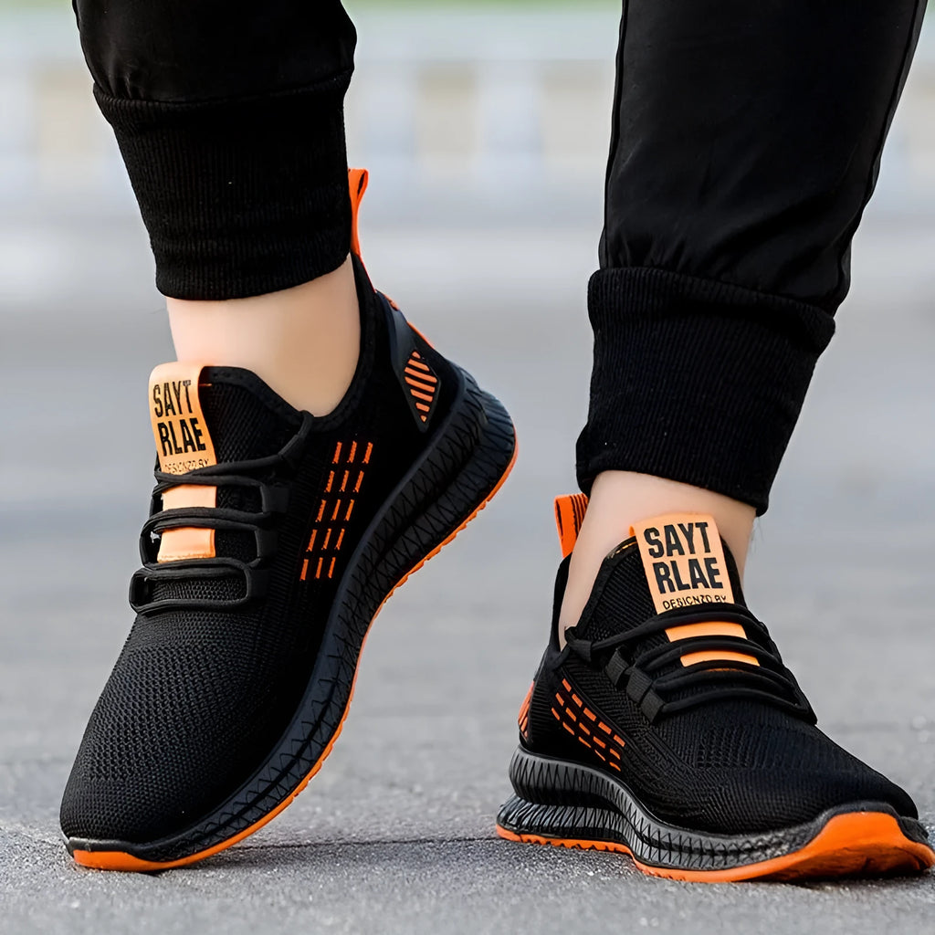 Men's black casual low-top trainers with flying weave upper, cross straps, and a striped pattern.