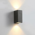 Satin black aluminium and glass LED wall lamp mounted on an interior wall.