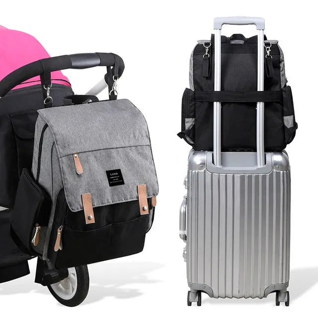 LAND Mommy large grey diaper backpack with changing mat, shown with baby care items.