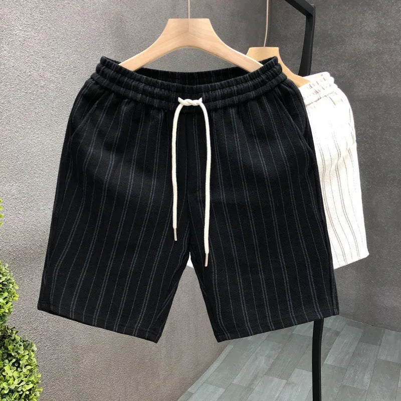 Man's black and white striped casual shorts with elastic waistband on a plain background.
