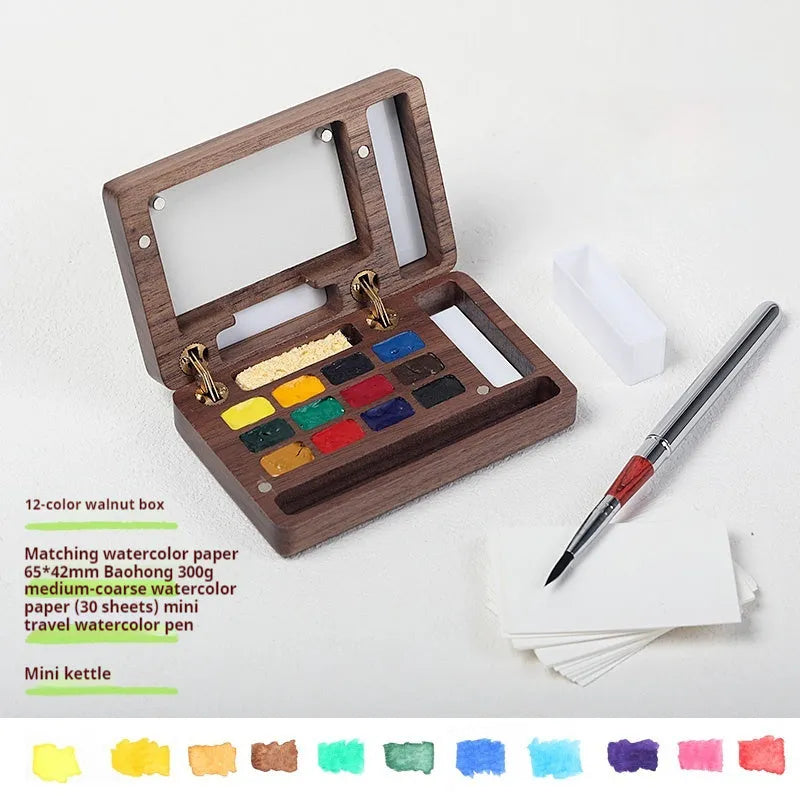 Mini walnut wooden watercolour paint box set with leather carry case, open to show professional artist pigments.