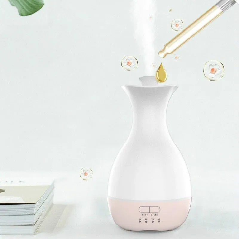 White ultrasonic aromatherapy diffuser and humidifier with colourful LED light misting on a wooden table.