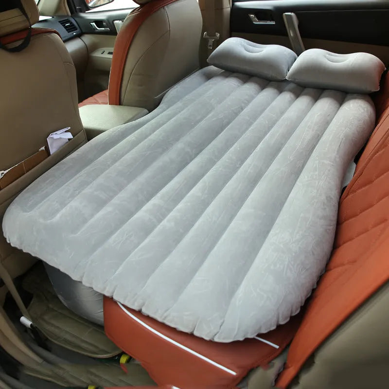 Black inflatable car bed with flocking surface and two pillows, shown folded next to a storage bag.
