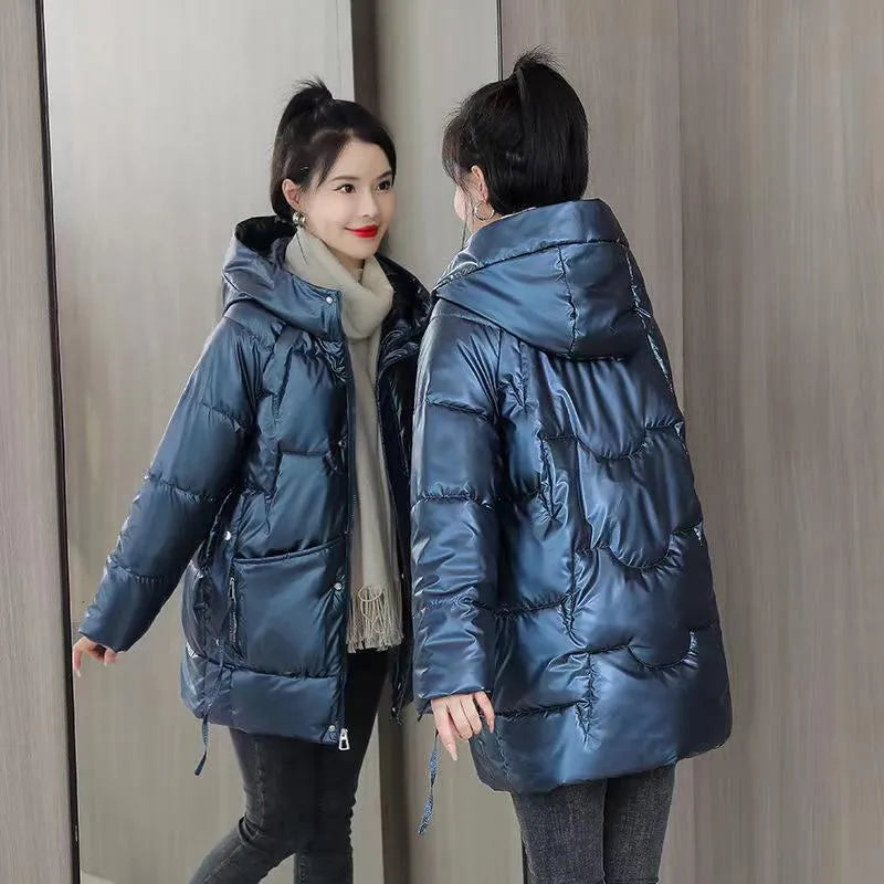 A green loose-fit hooded winter jacket for women on a hanger, showing long sleeves and thick insulation.