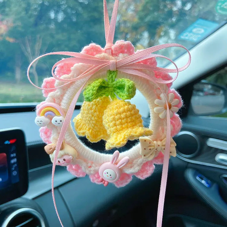 Handmade woven wool bell orchid car pendant on a green background, showing textured detail.