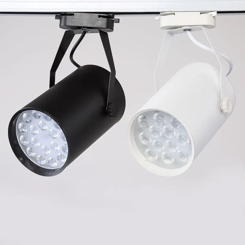 Black aluminium LED track spotlight with sliding head mounted on a track for wall lighting.