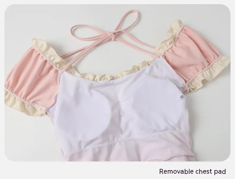 Pink women's one-piece swimsuit with Siamese design on a mannequin.