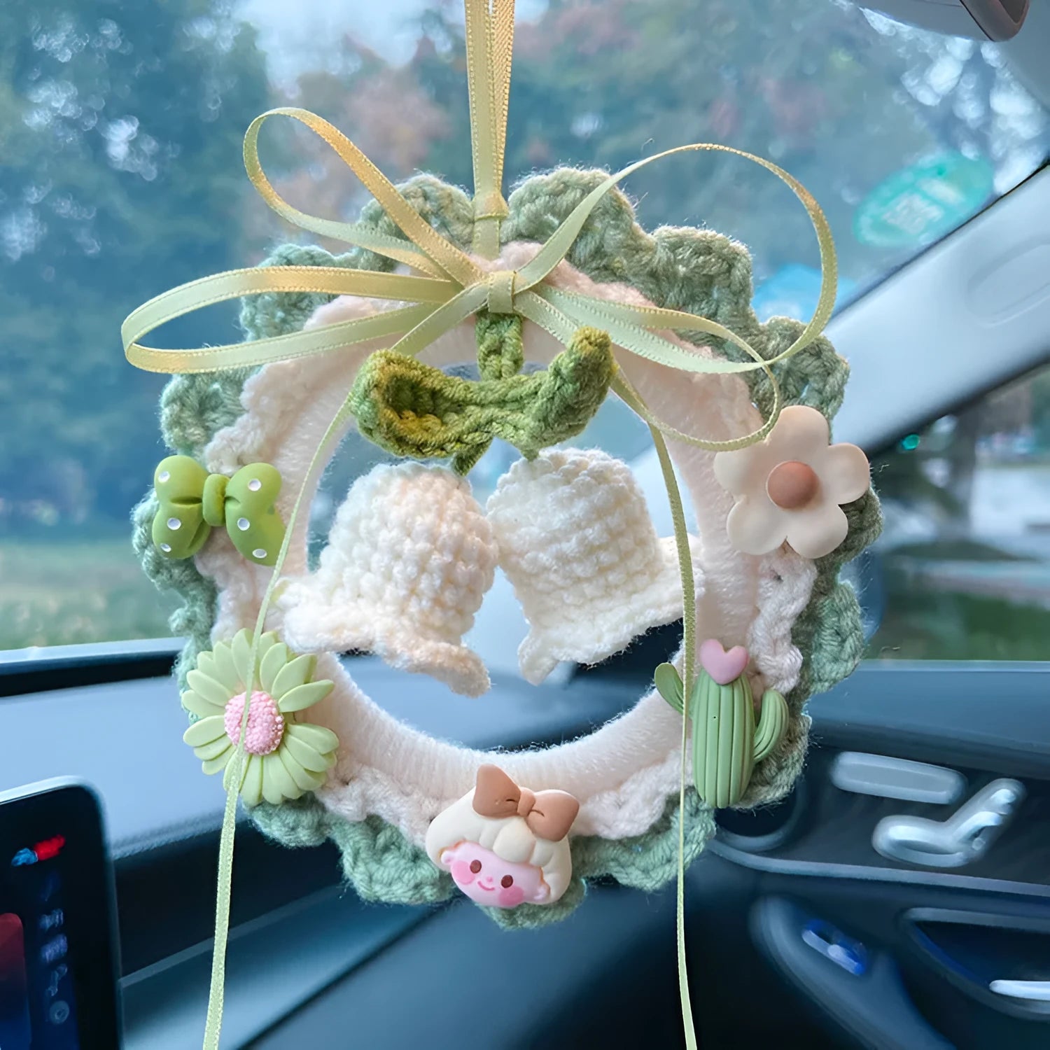 Handmade woven wool bell orchid car pendant on a green background, showing textured detail.